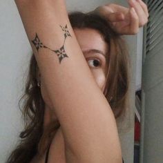 a woman with a tattoo on her arm is looking at the mirror and holding her hair in one hand