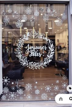 a store front window decorated with white snowflakes and wreaths that say joyeuxes better