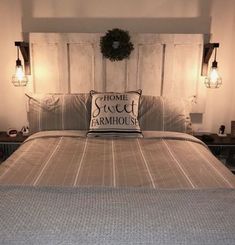 a bed that has some lights on the headboard and pillows in front of it