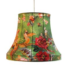 a green lamp shade with red flowers and birds on the bottom, hanging from a metal rod