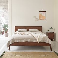 a bed with white sheets and pillows in a room next to a rug on the floor