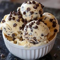 three scoops of ice cream in a bowl with chocolate chips on the top and bottom