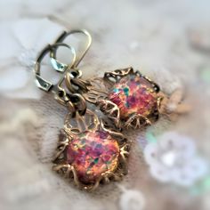 Hand crafted Art Deco Era, Lalique style inspiration, glass fire opal earrings. The stones have a pink base, with highlights of gold, aqua, green and red. When they catch the light, they seem to glow with fire from within.  I hand sculpted the filigree setting for them.  * Drop approx. .75" L x 5/8" W (19mm L x 16mm W)   *   Full length including ear wires approx. 1.5" L (33mm L)  * Finish: Antique gold-tone patina on solid brass.  * Stone: Glass fire opals are premium quality unworn vintage stock, Artisan made in Czechoslovakia.  * Solid brass hand forged ear wires * All metal components are high quality solid brass, lead and nickel free. * Packaged in a beautifully presented gift box with organza ribbons ready for gifting Limited Availability: Each piece is handcrafted and unique, availa Handmade Multicolor Fantasy Jewelry, Handmade Fantasy Jewelry For Party, Handmade Fantasy Style Jewelry For Parties, Handmade Iridescent Metal Jewelry, Artistic Dangle Jewelry For Party, Artistic Dangle Party Jewelry, Metal Earrings With Artistic Design For Gifts, Artistic Pink Jewelry For Party, Unique Festive Jewelry With Ear Wire