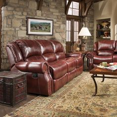 a living room with two couches and a coffee table in front of a stone wall