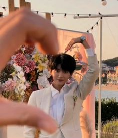 a man in a suit and tie holding his hands up to the sky with flowers on it