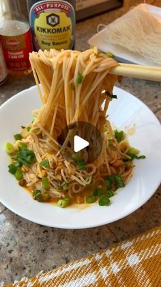 a white plate topped with noodles and veggies on top of a kitchen counter