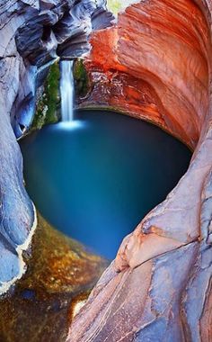 there is a small waterfall in the middle of this lake with blue water and rocks