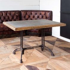 a table sitting on top of a wooden floor next to a brown leather couch in a living room