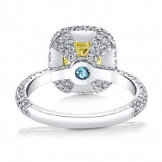 a yellow and white diamond ring with two blue diamonds on the side, set in 18k white gold