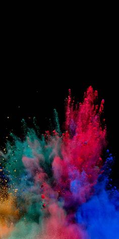 colorful powder is thrown into the air on a black background