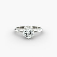 a white gold engagement ring with a round brilliant cut diamond in the center, on a plain surface