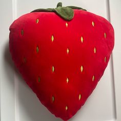 a red stuffed strawberry hanging on the wall