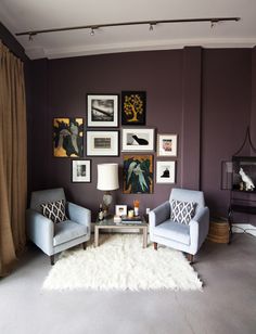 a living room with two chairs and pictures on the wall above them, in front of a window