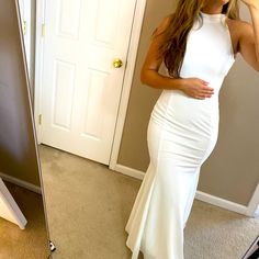 a woman taking a selfie in front of a mirror wearing a white long dress