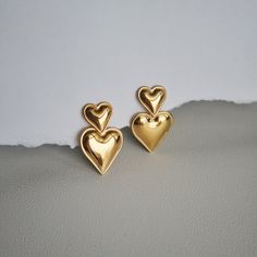 The Double Heart Drop Earrings will add a touch of love to any outfit. With their playful dangle design and bold heart shape, they're the perfect statement earrings for a girls night out or date night. Perfect for anyone who wants to show off their fun-loving side and spread lots of love wherever they go! - stainless steel, gold plated Double Heart Earrings For Mother's Day, Trendy Heart Charm Earrings For Mother's Day, Chic Heart Earrings For Parties, Trendy Dangle Heart Earrings For Valentine's Day, Heart Earrings For Mother's Day Party, Trendy Heart Earrings For Mother's Day, Mother's Day Double Heart Pierced Earrings, Heart Shaped Metal Earrings For Valentine's Day, Heart-shaped Metal Earrings For Valentine's Day