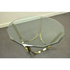 a glass and brass coffee table with curved legs