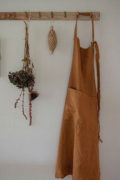 an apron hanging on a wall next to dried flowers and other things that are attached to the wall