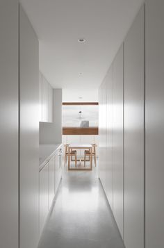 a long white hallway leading to a table and chairs