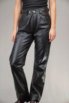 These striking vintage leather pants, likely from the 1980s, are crafted from supple, genuine black leather. The high-waisted design and relaxed leg fit channels the bold energy of the era, blending effortlessly into modern trends that favor quality craftsmanship and timeless appeal. Leather, known for its durability and luxurious texture, gains character as it ages, making these pants not just a wardrobe statement but a long-lasting investment piece. In excellent vintage condition, without any Black Leather Bottoms With Belt Loops, Black Straight Leg Leather Pants With Belt Loops, Black Retro Fall Pants, High Waist Leather Bottoms For Streetwear, Black High-waisted Leather Pants For Streetwear, Black Leather Pants With Pockets, High-waisted Leather Pants For Streetwear, High Waist Leather Pants For Streetwear, High Waist Black Leather Pants For Streetwear