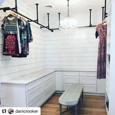 a closet with clothes hanging on the wall and a chandelier in the corner