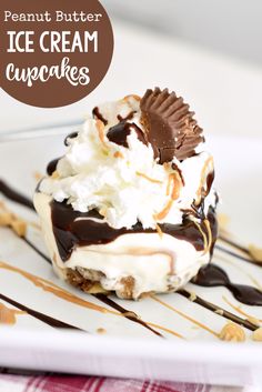 an ice cream cupcake with chocolate sauce and whipped cream on top is sitting on a white plate