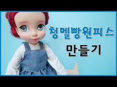 a doll with red hair and blue overalls standing in front of a sign that says hello