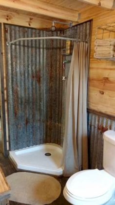 a bathroom with a shower, toilet and sink in it's own stall that is made out of corrugated