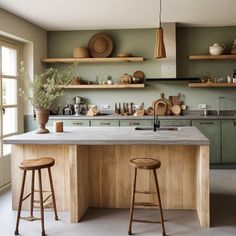 a kitchen with two stools in front of an island