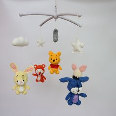 three crocheted stuffed animals hanging from a mobile with stars on the ceiling above them