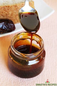 a spoon full of peanut butter and jelly on top of a plate with bread in the background