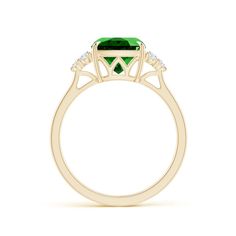 an emerald and diamond ring with three diamonds on the shoulders, set in yellow gold