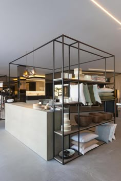 an open kitchen and dining room area in a modern style house with white walls, concrete flooring and black metal shelving