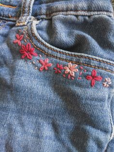 a pair of jeans with flowers embroidered on them