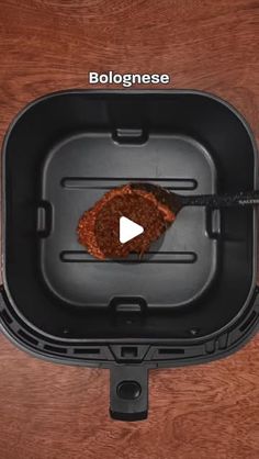 a piece of meat in a black container on top of a wooden table with the words bolognaese written above it