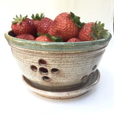 a bowl filled with strawberries on top of a table