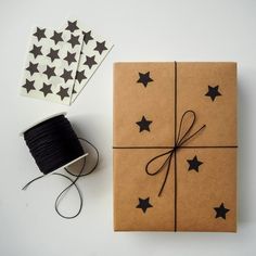 a brown box with black stars on it next to a spool of thread and twine