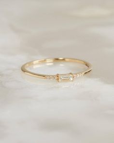 a gold ring with three stones on it, sitting on a white furnishing