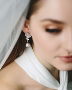 a woman wearing a veil and earrings with pearls on the back of her head is looking down