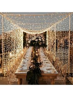 a long table with white flowers and lights on it