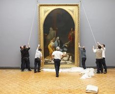 people are doing different things in front of a painting