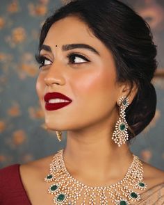 a woman wearing a necklace and earrings with green stones on her neck, looking to the side