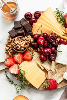 an assortment of cheeses, fruit and nuts on a platter