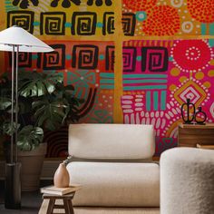 a living room with colorful wallpaper and floor lamp next to couch in front of large potted plant