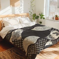 a bed with a black and white quilt on top of it next to a window