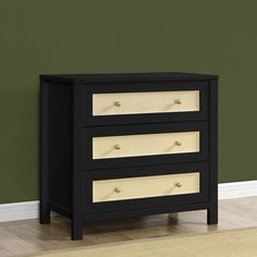 a black and white dresser with three drawers in front of a green wall on the floor