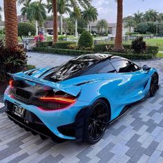 a blue sports car parked in front of palm trees