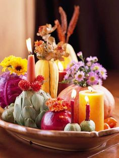 a bowl filled with candles and flowers on top of a table