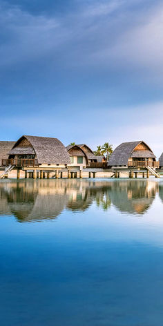 the water is clear and blue with some huts on it