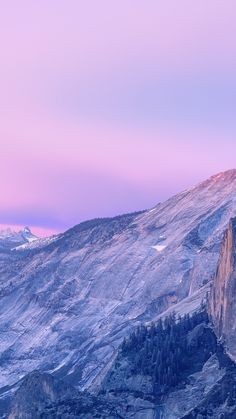 there is a mountain with snow on it and trees in the foreground at sunset