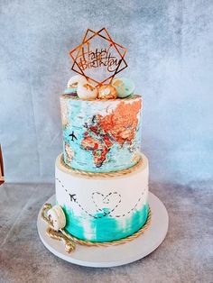 a three tiered cake decorated with an earth map and gold decoration on top is sitting on a white plate